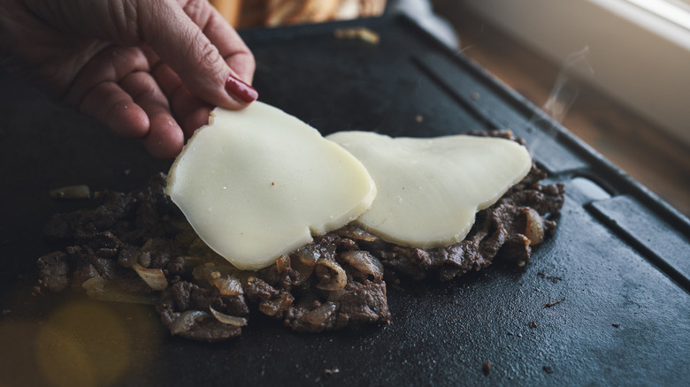 Cheesesteak meat on flattop grill with provolone