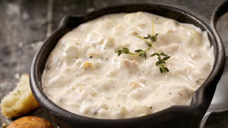 A cast iron pot of New England clam chowder with chunky potatoes and clams