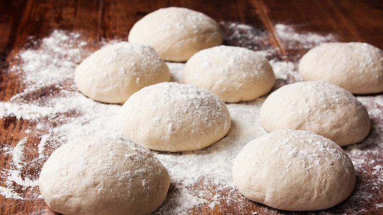 collection of pizza dough balls on a board