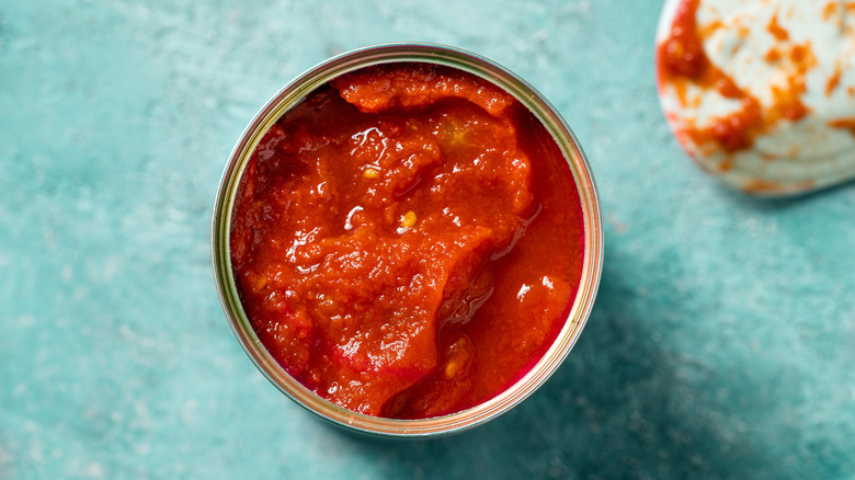 open can of tomato sauce on blue background