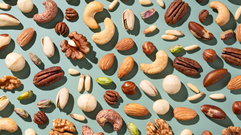 Assorted shelled nuts sit on a teal background.