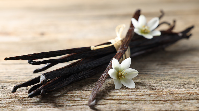 dried vanilla bean pods and fresh flowers are arranged