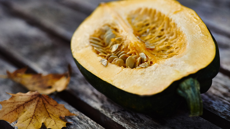 halved acorn squash with seeds sitting on wood background