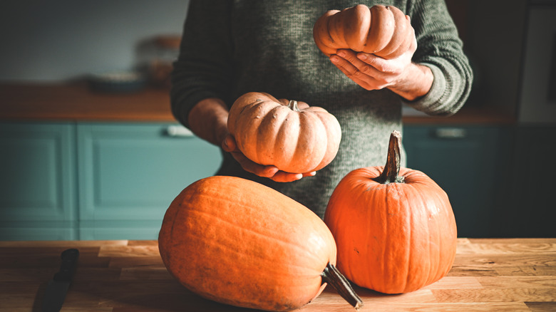 person in kitchen with four pumpkins