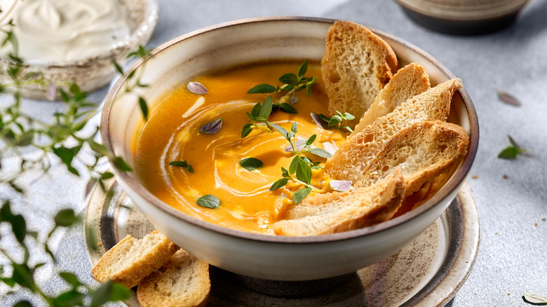 squash and carrot soup in ceramic bowl with bread