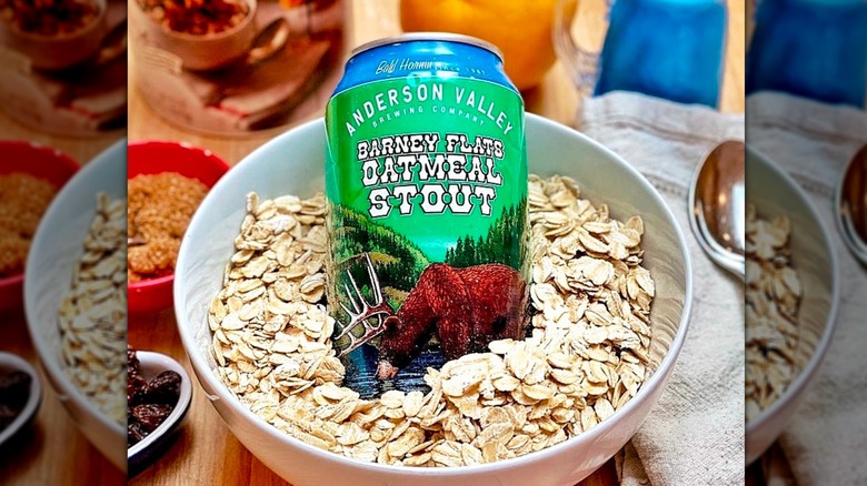 A can of Barney Flats oatmeal stout in a white bowl of oats with breakfast dishes in the background