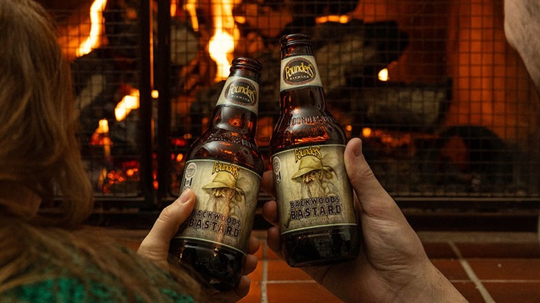 A man and women cheers with Backwoods Bastard ale in front a fireplace