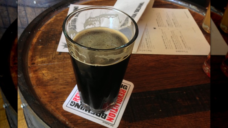 A glass of dark beer on a Revolution Brewing coaster on a wooden table