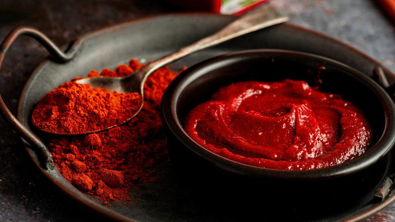 red gochujang powder and sauce on black dishes on table