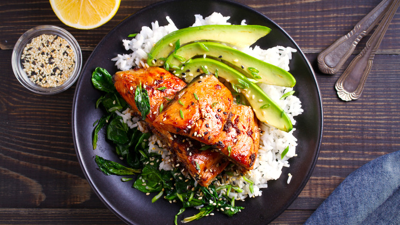 honey glazed salmon on a bed of rice with avocado slices served on table