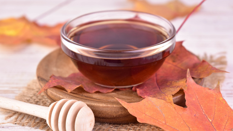 small glass bowl with maple syrup and maple leaves