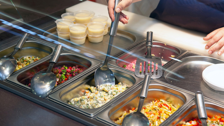 Someone serving buffet food out of their containers