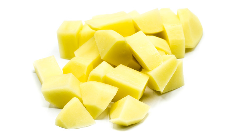 raw potato cubes on white background