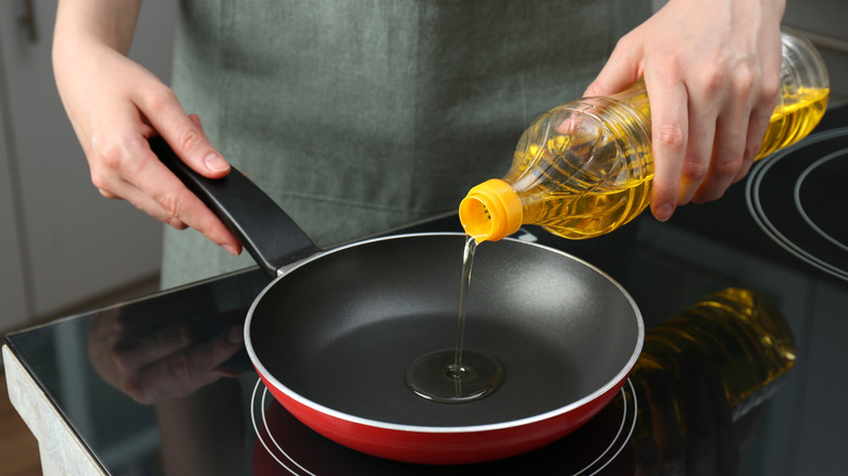 person pouring cooking fat into a pan