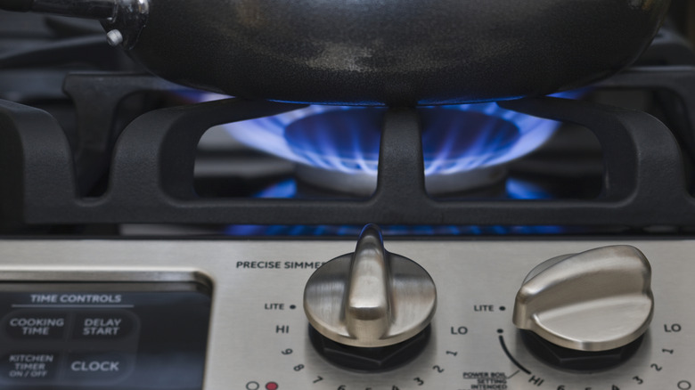 gas stovetop with pan and lit burner