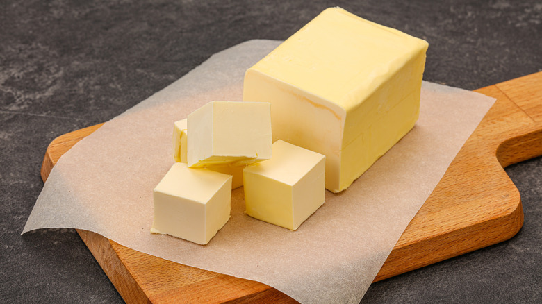 block of butter cut in cubes on wooden board