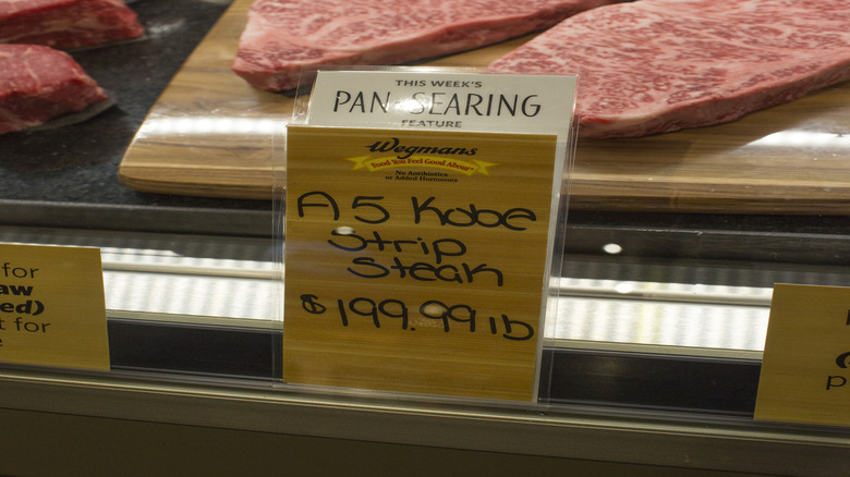 Two A5 Wagyu strip steaks in a butcher case at Wegmans with a Wegmans label in front