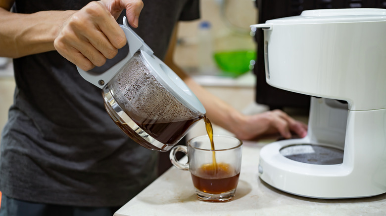 person pouring brewed coffee into a cup