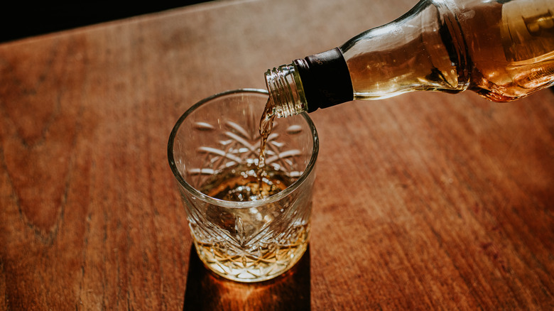 Whiskey pouring from a bottle into a glass