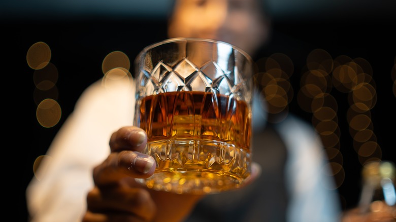 Person serving a glass of whiskey