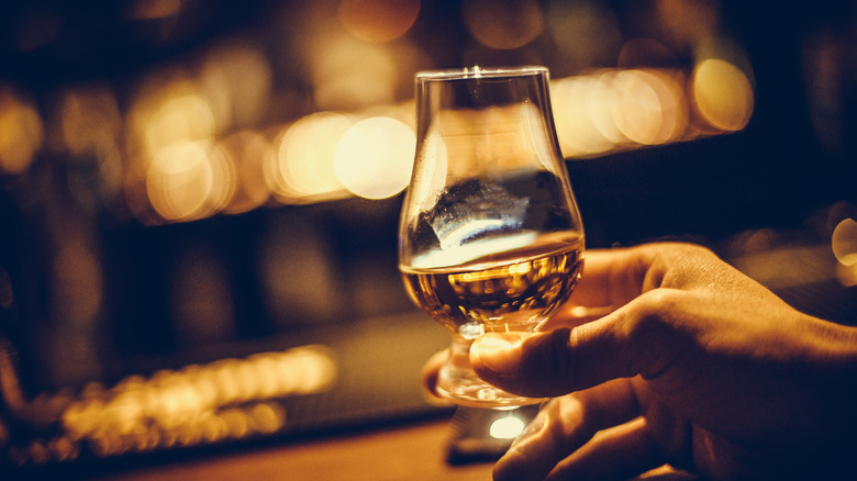 A hand holding a Glencairn whiskey tasting glass