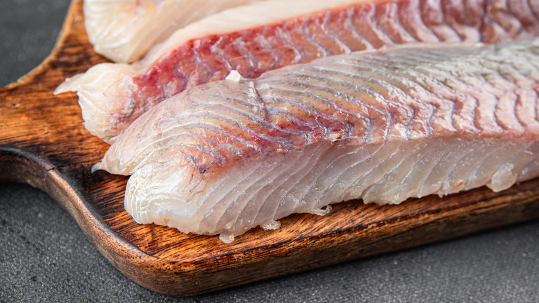 Raw fish fillets on wooden board