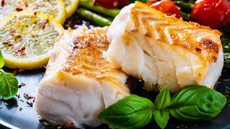 Seared cod fillets with lemon and garnish on plate