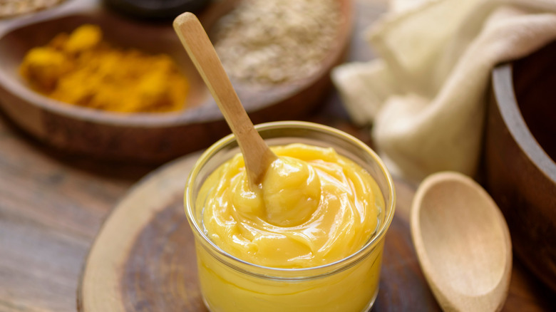 Ghee in glass jar with wooden spoon