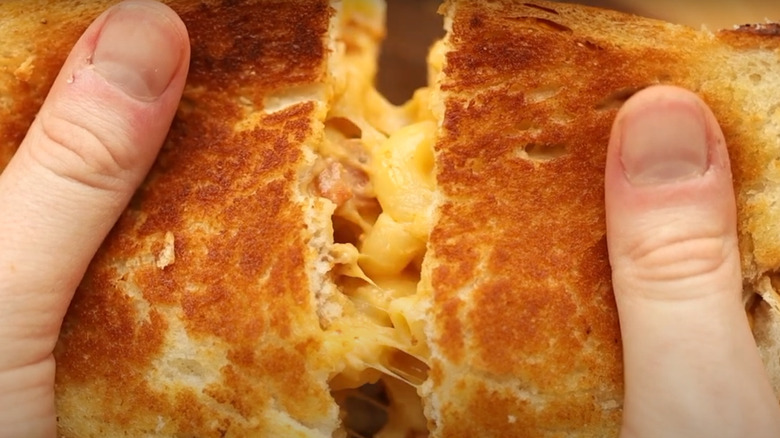 Hand pulling apart a grilled mac and cheese sandwich