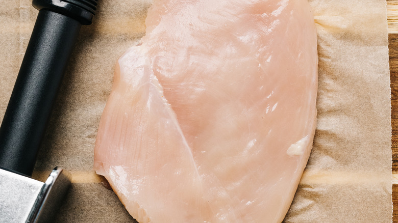 raw chicken and tenderizer on parchment paper