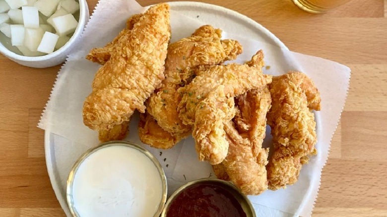 a plate of chicken tenders and two sauces
