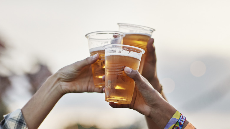 Three people raising glasses of beer