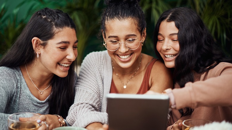 three women smile at menu