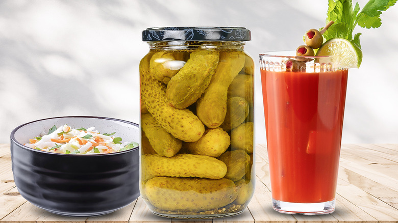 A jar of pickles with a bloody mary and bowl of coleslaw