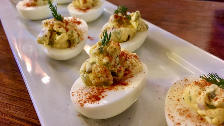 A plate of deviled eggs with paprika and dill