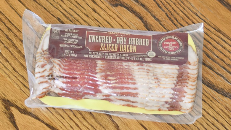 A package of Trader Joe's uncured dry rubbed sliced bacon on a wooden table