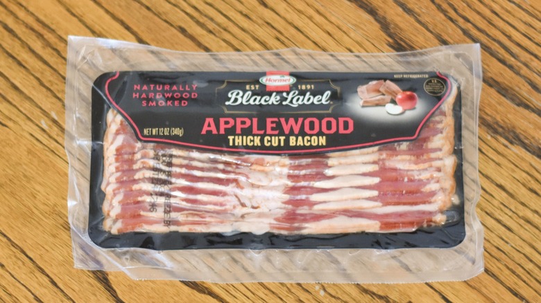 A package of Hormel Black Label applewood thick cut bacon on a wooden table