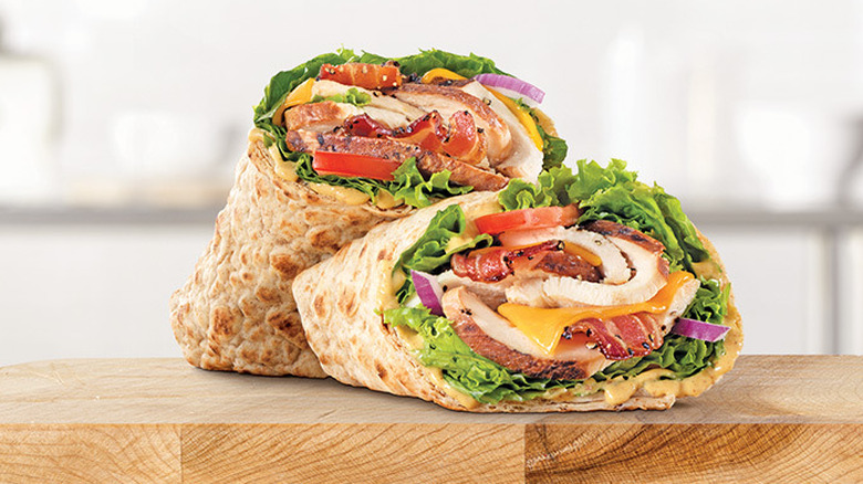 Arby's Crispy Chicken Club Wrap cut in half sitting on a cutting board