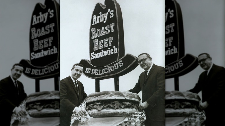 Arby's founders Leroy Raffel and Forrest Raffel in front of the Arby's sign with a giant roast beef sandwich