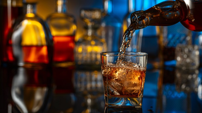 Whiskey poured from a bottle into a glass