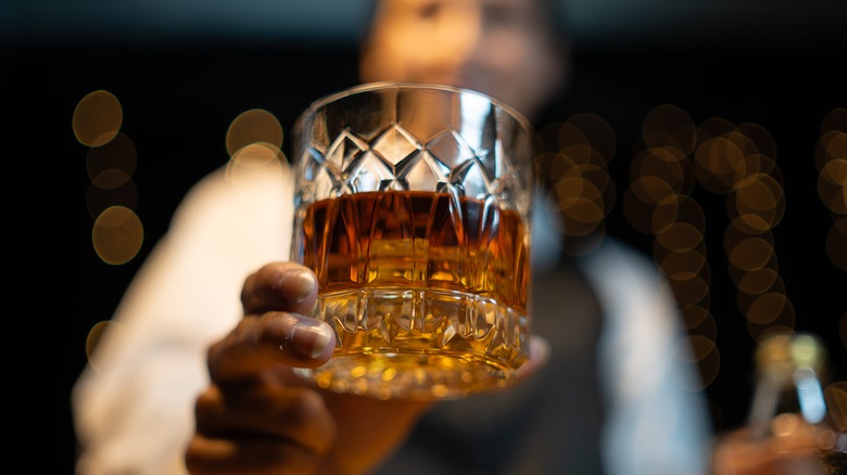 Bartender holding a crystal glass of whiskey