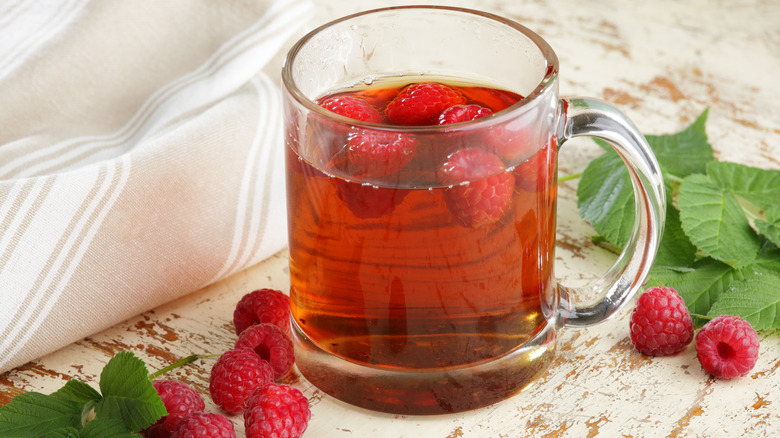 Glass mug of tea with raspberries