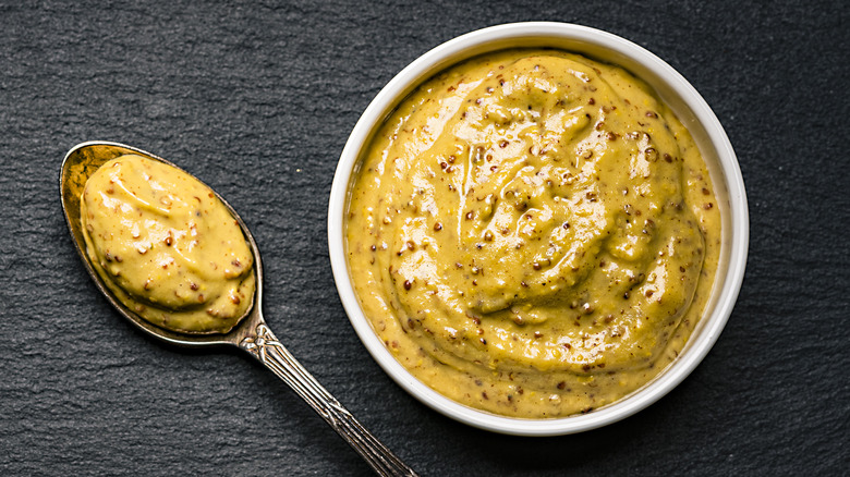 A ramekin of mustard and with a spoon