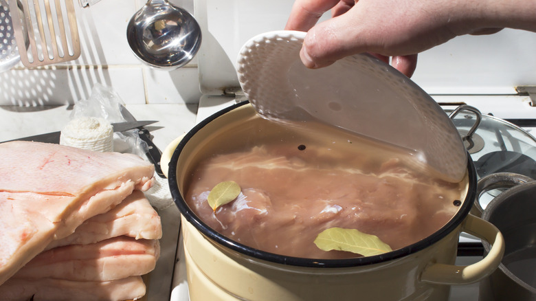 Soaking raw meat in brine on stove next to other cuts of raw meat