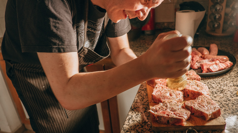 A person seasoning pork chops
