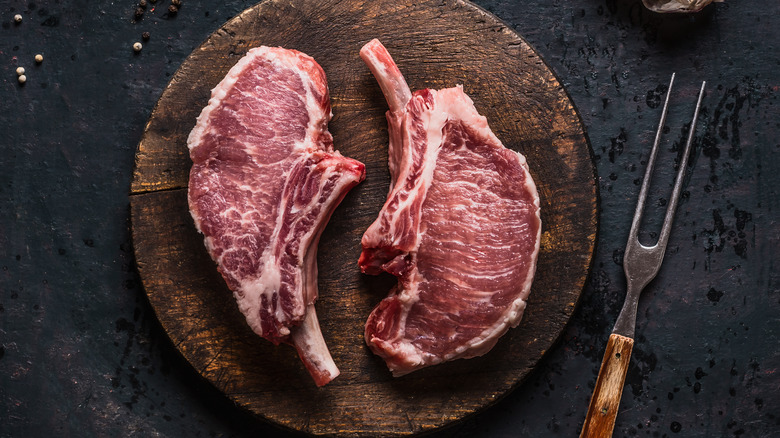 Two raw Iberico pork chops on a cutting board