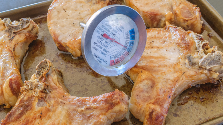 A tray of pork chops with a meat thermometer