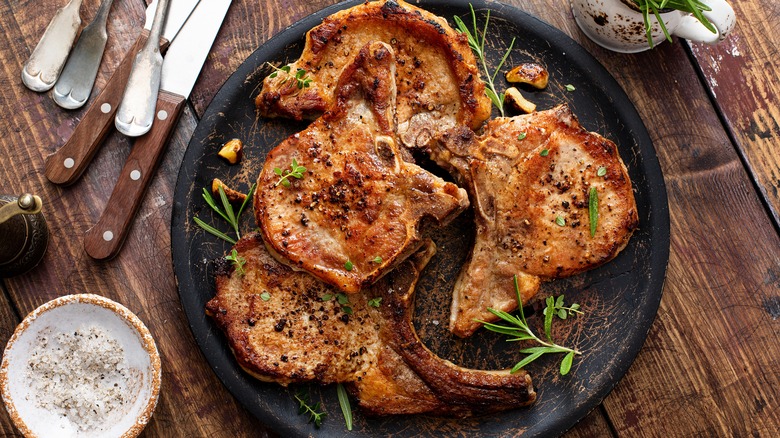 Four cooked pork chops resting on a plate