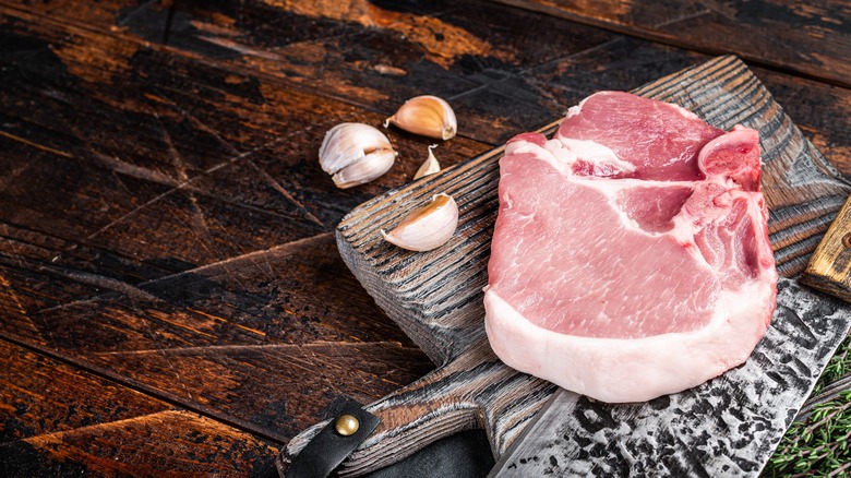 A thick-cut raw pork chop on a cutting board