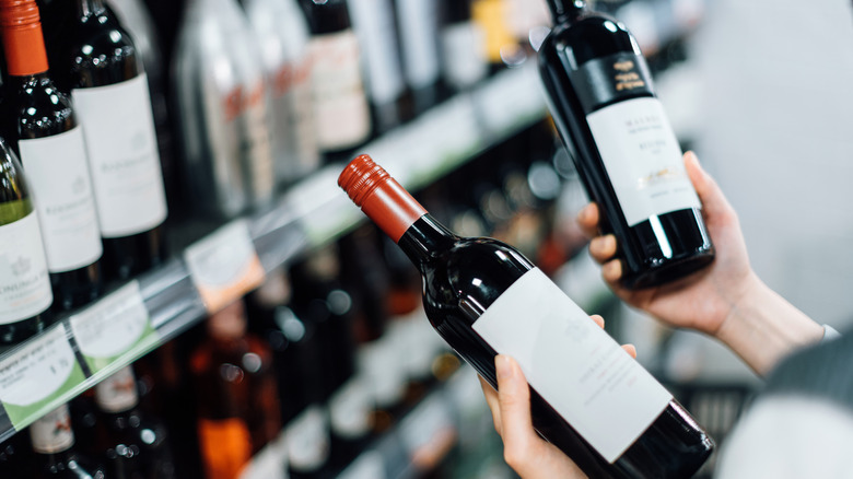 Woman choosing red wine at store